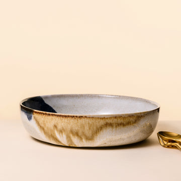 beige natural coloured bowl with a dark blue and gold glaze unevenly applied for an artistic touch